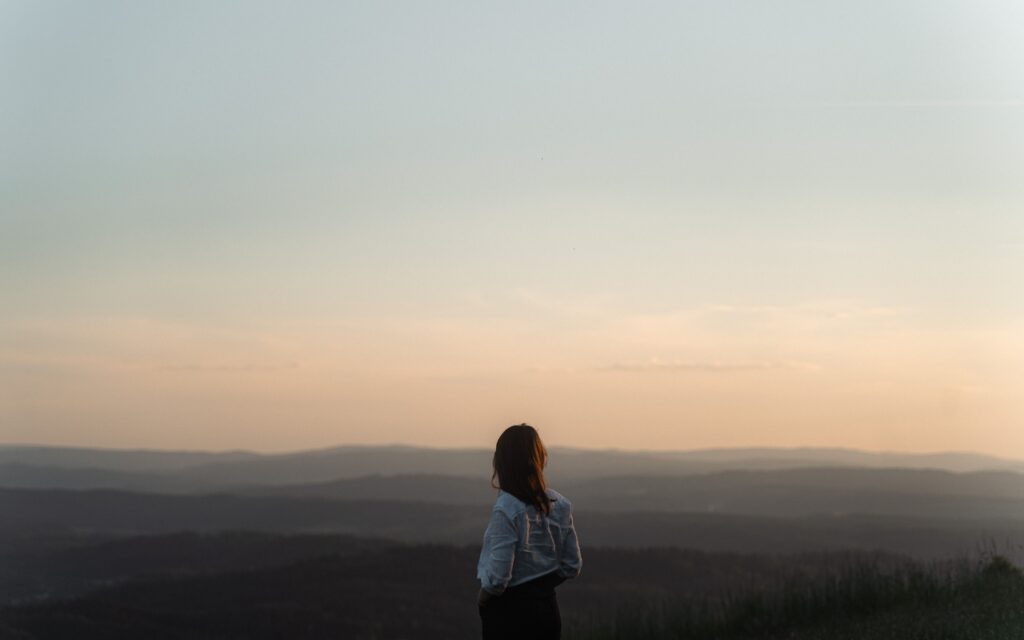 A woman gazes over the tranquil horizon at sunset in Solina, Poland.